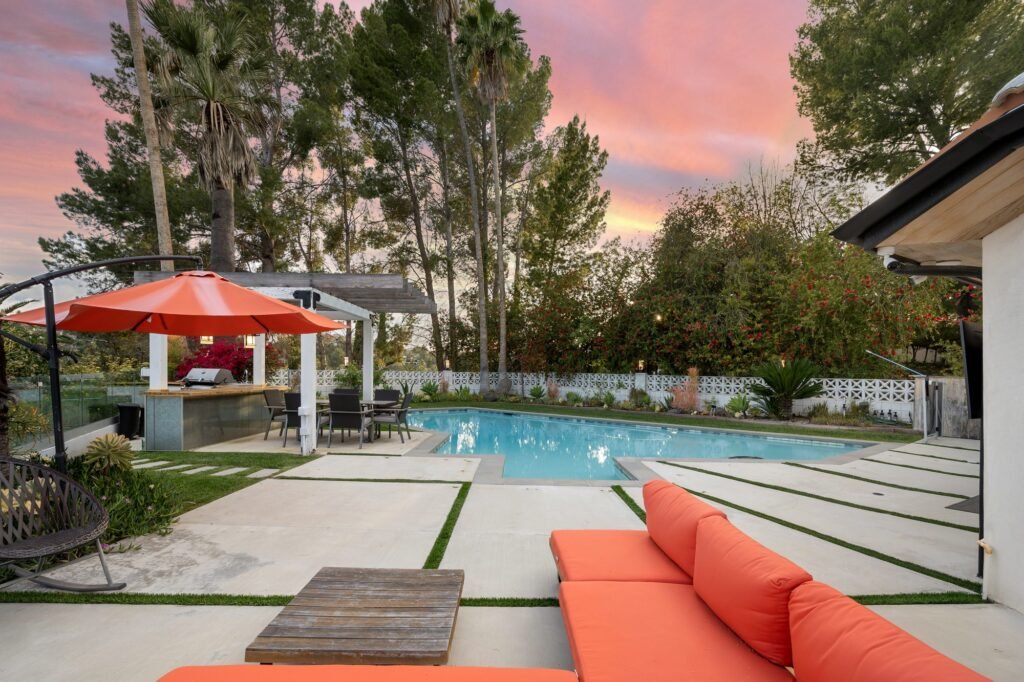 a swimming pool sitting next to a covered patio area with patio furniture